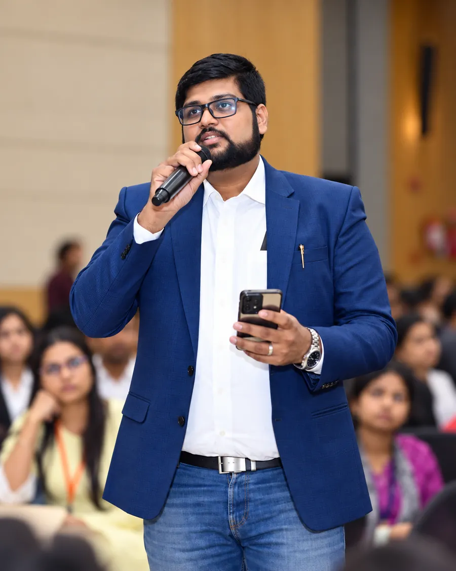 Angad Kulkarni speaking with a microphone in a lecture hall